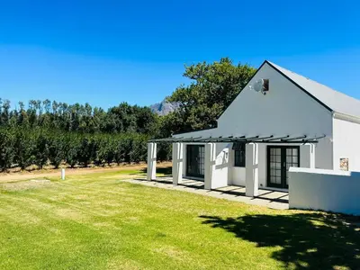 a white building with a large yard with a grass field at Allèe Bleue Wine Estate in Simondium