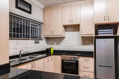 a kitchen with wooden cabinets and a stainless steel refrigerator at Avemore Vredehof No 2 - full Backup Power in Stellenbosch