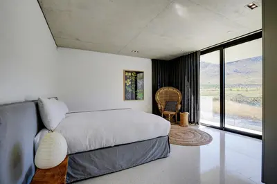 a bedroom with a bed and a large window at Restio River House in Pringle Bay