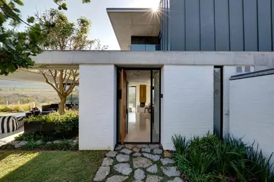 a white brick house with a glass door at Restio River House in Pringle Bay