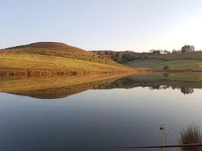 a body of water with a hill in the background at Paul Wallace Wines & Cottages in Elgin