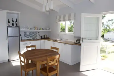 a white kitchen with a wooden table and chairs at Paul Wallace Wines & Cottages in Elgin
