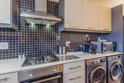 a kitchen with a stove and a washer and dryer at Quayside 301 by CTHA in Cape Town