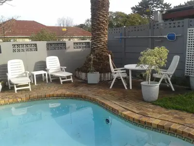 a pool with chairs and a table and a tree at brookdale house in Cape Town