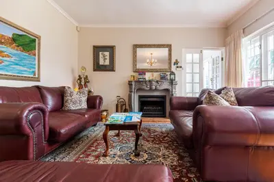 a living room with leather furniture and a fireplace at brookdale house in Cape Town