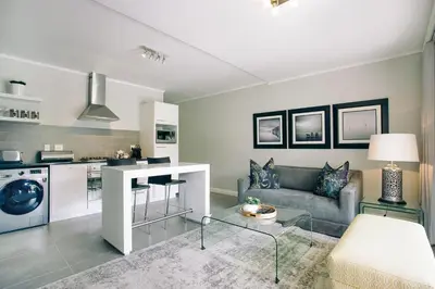 a living room with a couch and a kitchen at Superior Apartment Mayfair in Cape Town