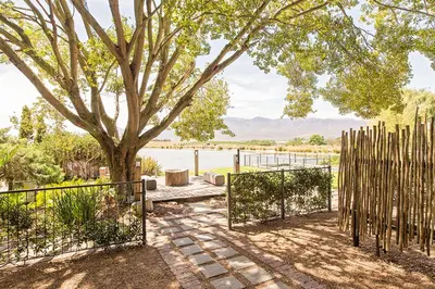 a fence next to a tree with a gate at Waterside on Le Bonheur in Simondium