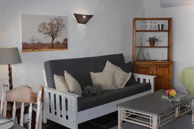a living room with a couch and a table at Waterside on Le Bonheur in Simondium