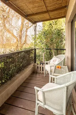 a porch with white wicker chairs and a table at Waterside on Le Bonheur in Simondium
