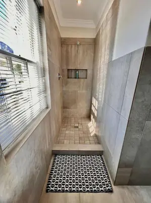 a bathroom with a shower with a black and white floor at Anesta House in Stellenbosch