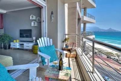 a room with a balcony with a view of the ocean at Portico 802 in Bloubergstrand