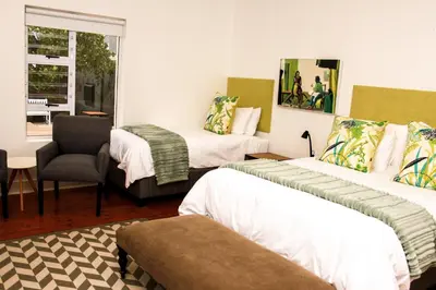 a room with two beds and a chair and a table at Hermanus Champagne Accommodation in Hermanus