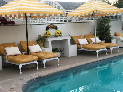 a pool with chairs and an umbrella next to a swimming pool at Our Hermanus House in Hermanus