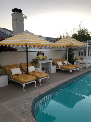 a swimming pool with chairs and umbrellas next to a swimming pool at Our Hermanus House in Hermanus