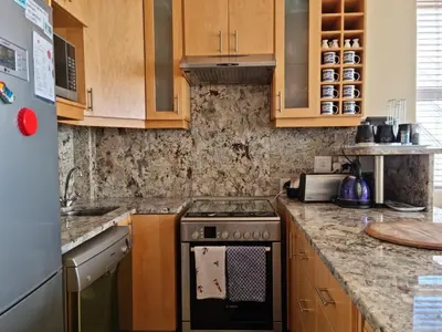 a kitchen with wooden cabinets and a stove top oven at 'The View' on Bikini Beach, Seafront, 2 bedroom, Sleeps 4 in Gordonʼs Bay