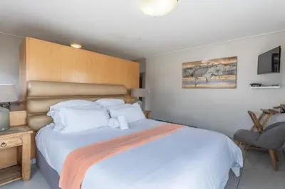 a bedroom with a large white bed and a chair at Manhattan Luxury Suite at Canal Walk in Cape Town