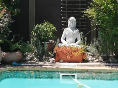 a statue sitting next to a pool next to aitatingitatingitatingitatingitatingitating at The Buddha Garden in Cape Town