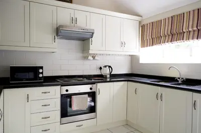 a kitchen with white cabinets and black counter tops at Laurel Cottage in Franschhoek
