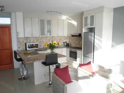 a kitchen with white cabinets and a counter with red pillows at 308 St Tropez in Strand