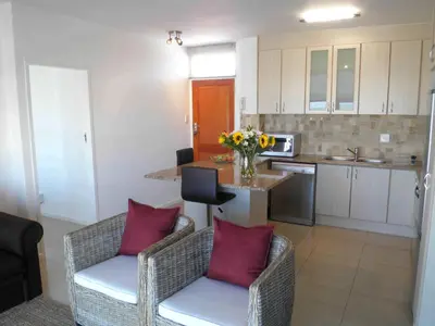 a kitchen with two chairs and a table with flowers at 308 St Tropez in Strand