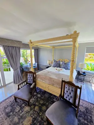 a bedroom with a canopy bed and two chairs at Hermanus Manor in Hermanus