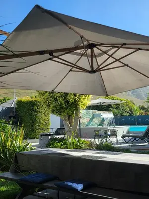 a large tan umbrella sitting next to a pool at Hermanus Manor in Hermanus