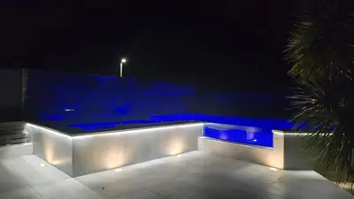 a pool with blue lighting at night with a palm tree at Hermanus Manor in Hermanus