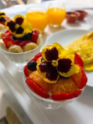 a plate of fruit with flowers on top of it at Hermanus Manor in Hermanus