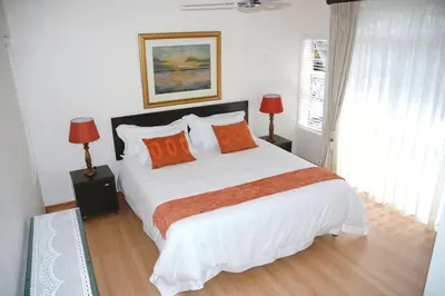 a bedroom with a large white bed with orange pillows at Edelweiss Bed & Breakfast in Stellenbosch