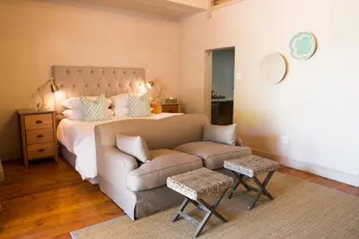 a bedroom with a bed and a couch and a chair at Mont d'Or Franschhoek in Franschhoek