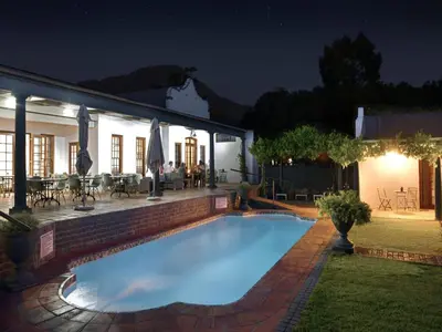 a swimming pool in the yard of a house at night at Mont d'Or Franschhoek in Franschhoek