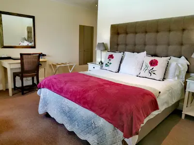 a bedroom with a large bed with a red blanket at Boutique Villa Guesthouse in Somerset West