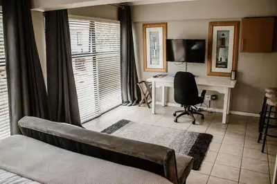 a living room with a couch and a desk with a computer at Concord Apartment in Stellenbosch