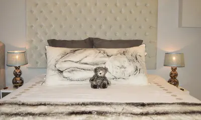 a teddy bear sitting on top of a bed at 1AA Wilhelmina Luxury Suites in Franschhoek