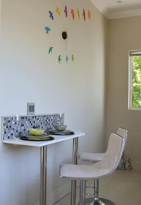 a kitchen with a table with chairs and a clock on the wall at 1AA Wilhelmina Luxury Suites in Franschhoek