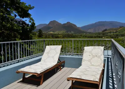 two chairs on a deck with mountains in the background at 1AA Wilhelmina Luxury Suites in Franschhoek