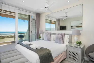 a bedroom with a bed with a view of the ocean at Dolphin Beach H106 in Bloubergstrand