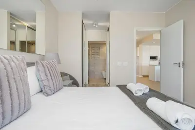 a bedroom with a large white bed with towels on it at Dolphin Beach H106 in Bloubergstrand