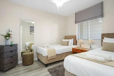 a bedroom with two beds and a mirror at Dolphin Beach H106 in Bloubergstrand