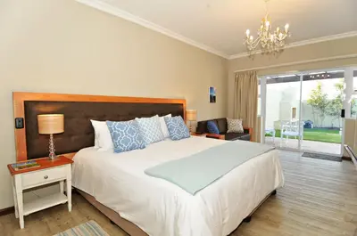 a bedroom with a large bed and a chandelier at The Gables Hermanus in Hermanus