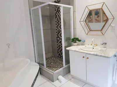 a white bathroom with a shower and a sink at Zonnevanger Guesthouse in Noorder-Paarl
