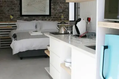a bedroom with a bed and a kitchen with a sink at No. 9 Keurboom in Cape Town
