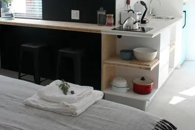 a bed with a stack of towels on it next to a kitchen at No. 9 Keurboom in Cape Town