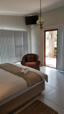 a bedroom with a large bed and a chair at Guest House Frame Ace in Bellville