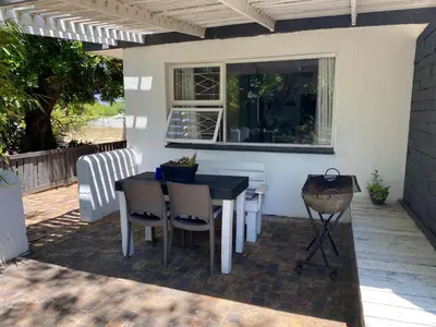 a patio with a table and chairs and a window at Willows Curve in Somerset West