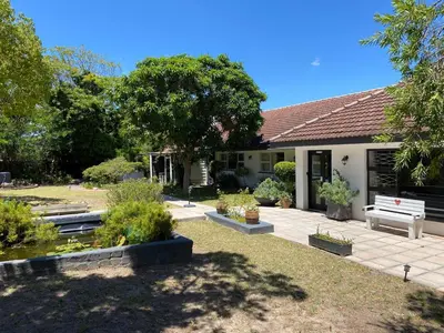 a house with a garden and a white bench at Willows Curve in Somerset West
