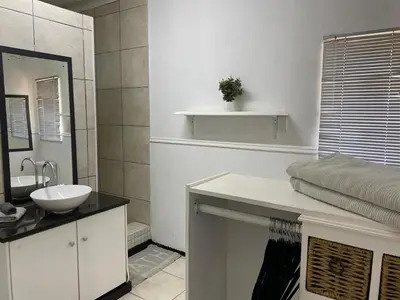 a white bathroom with a sink and a mirror at Willows Curve in Somerset West
