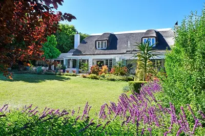 a house with a thatched roof and a garden at The Garden View Suite in Franschhoek