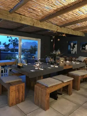 a restaurant with wooden tables and benches and a large window at Bloemenzee Boutique B&B in Gordonʼs Bay