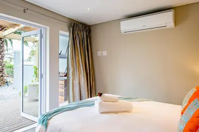 a bedroom with a bed and a balcony at Bloemenzee Boutique B&B in Gordonʼs Bay